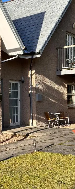 a house with a porch and a deck with a chair at Apartment in Queens Court, Banchory in Inchmarlo