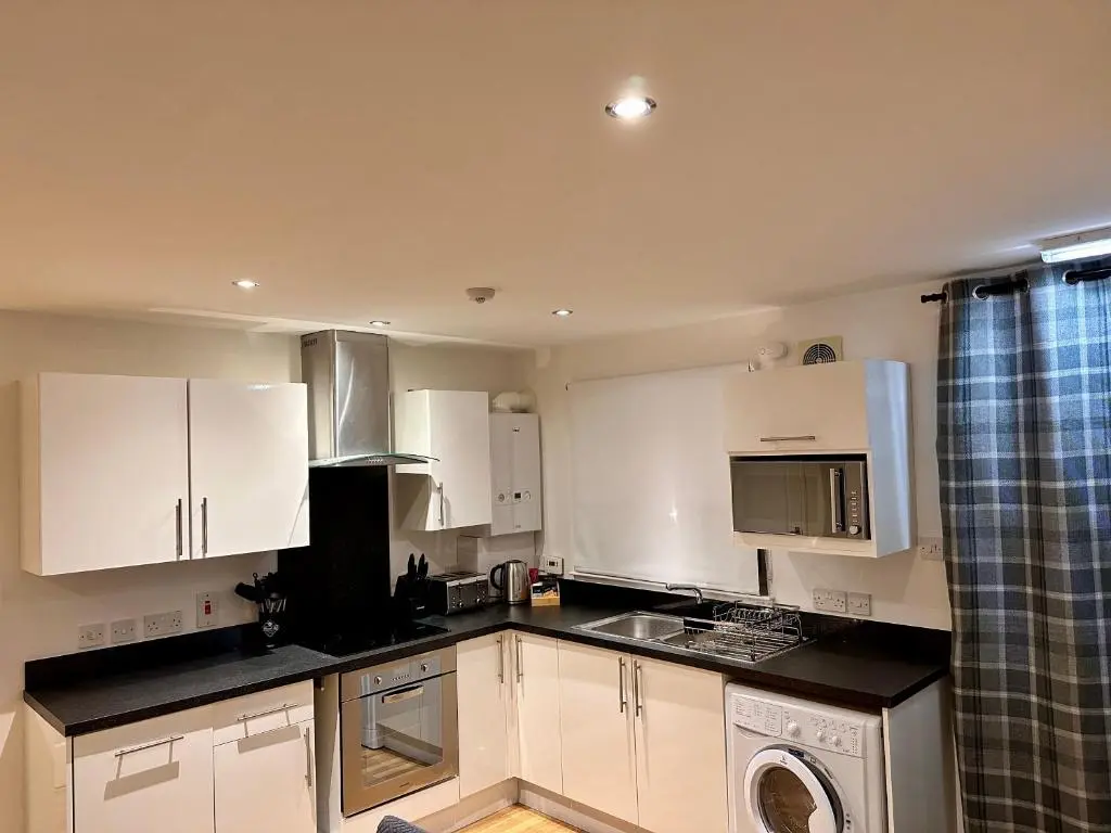 a kitchen with white cabinets and a washer at Apartment in Queens Court, Banchory in Inchmarlo