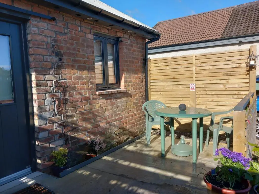 a patio with a table and chairs and a building at The Coo Shed in Inverness