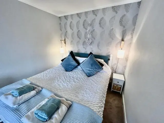 a bedroom with a blue and white bed with pillows at Above the harbour wick in Wick