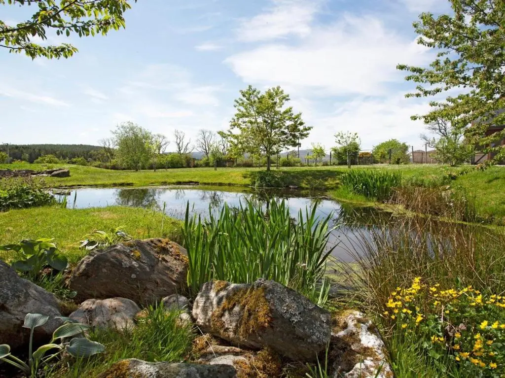 a pond in the middle of a field with rocks at 2 Bed in Ardross oc-ca384 in Stittenham