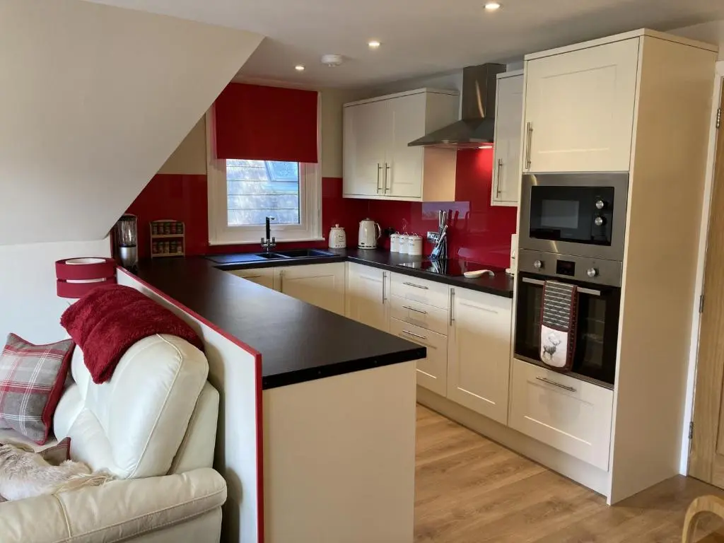 a kitchen with white cabinets and a black counter top at Lodge 24 in Spean Bridge