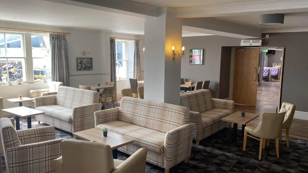 a waiting room with couches and tables and chairs at Caledonian Hotel 'A Bespoke Hotel\u2019 in Ullapool