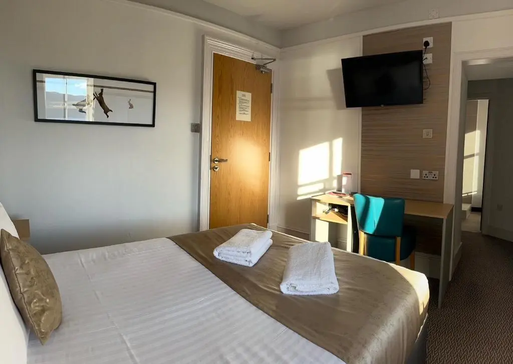 a hotel room with a bed and a desk and a television at Caledonian Hotel 'A Bespoke Hotel\u2019 in Ullapool