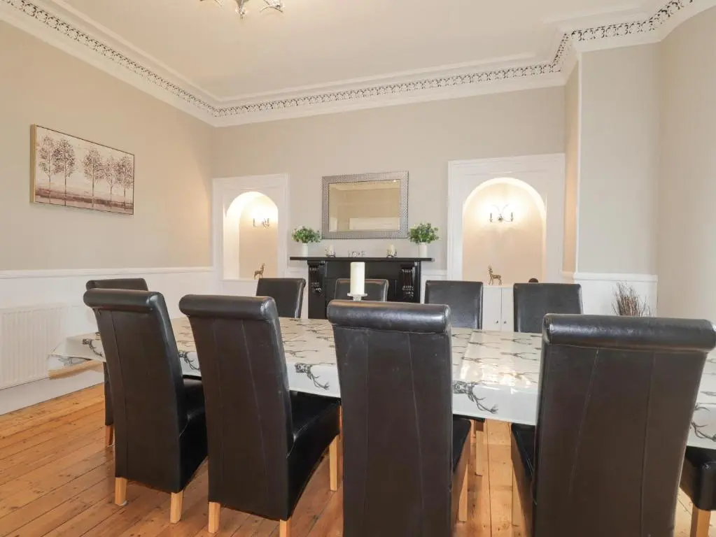 a dining room with a table and black chairs at Arden House in Kingussie