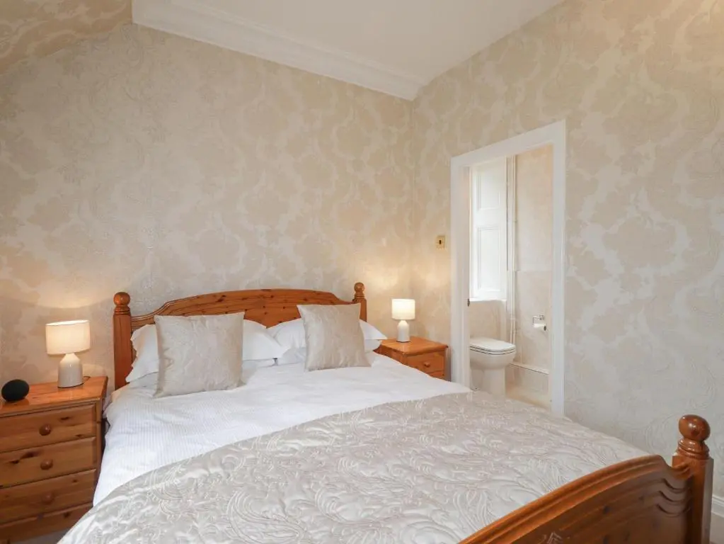 a bedroom with a large bed and two lamps at Arden House in Kingussie
