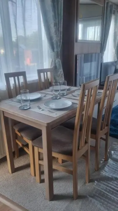 a wooden table with chairs and glasses on it at Coorie Nook, Chalet 103 in Aviemore