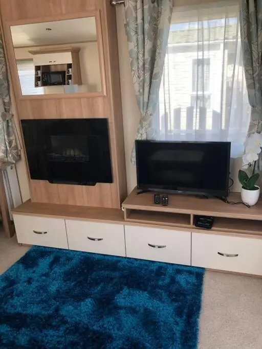 a living room with a flat screen tv on a entertainment center at Coorie Nook, Chalet 103 in Aviemore