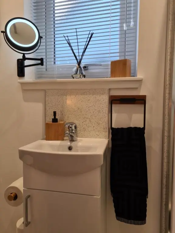 a bathroom with a sink and a mirror next to a window at Findon Nook in Culbokie