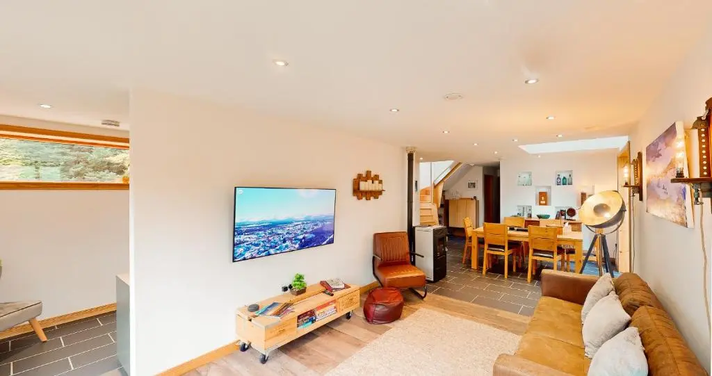 a living room with a couch and a dining room at Woodhaus Aviemore Lodge in Aviemore