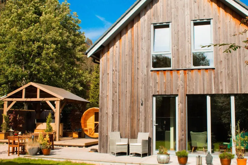 a wooden house with a patio and a gazebo at Woodhaus Aviemore Lodge in Aviemore