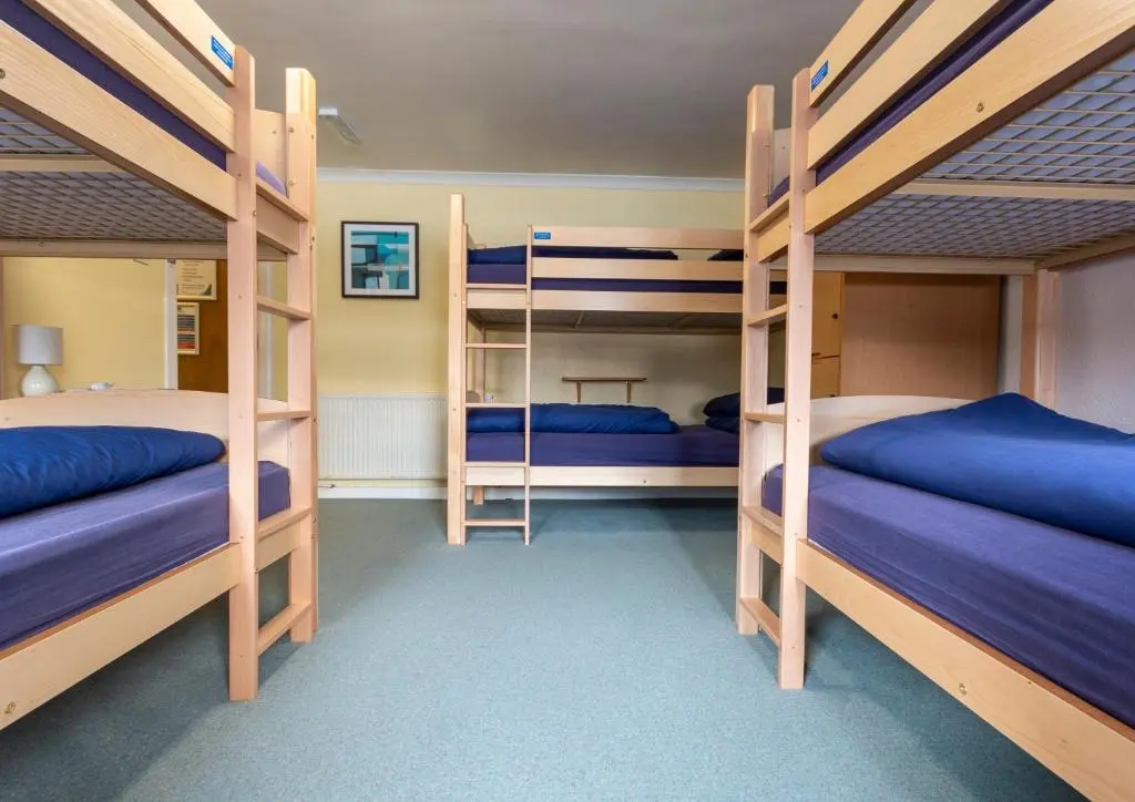 a room with three bunk beds with blue sheets at Ullapool Youth Hostel in Ullapool