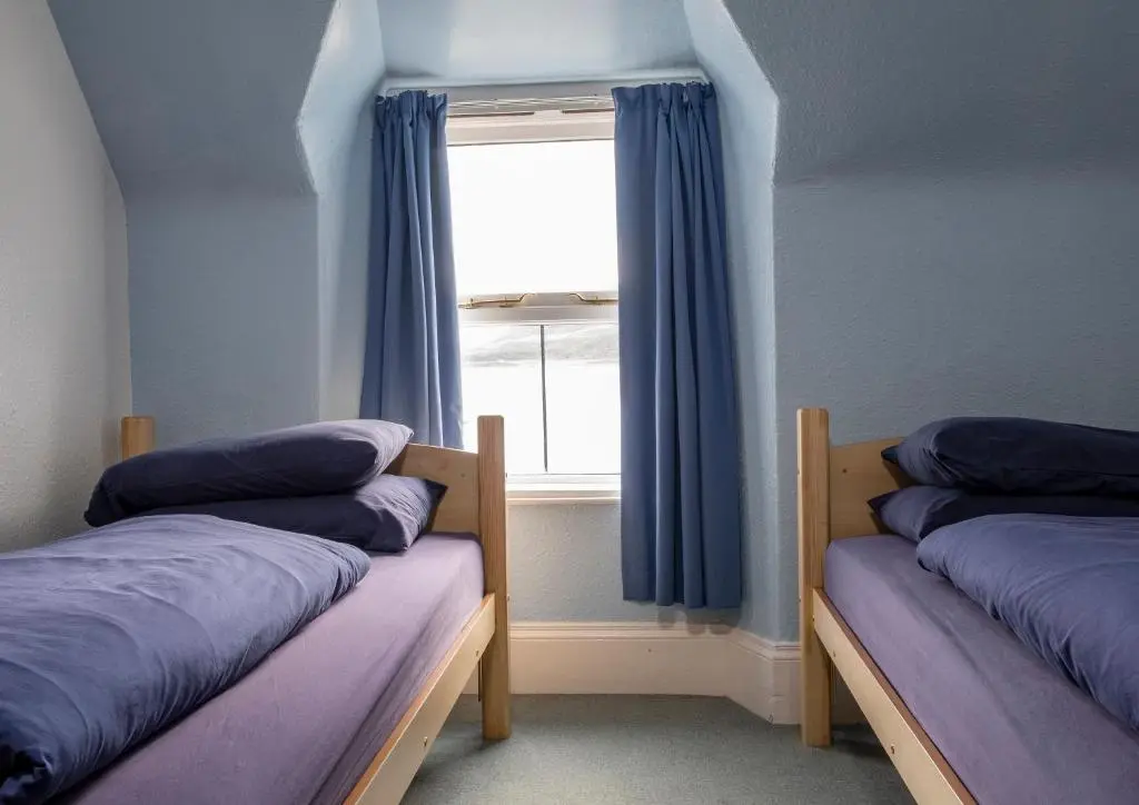 two beds in a room with a window at Ullapool Youth Hostel in Ullapool