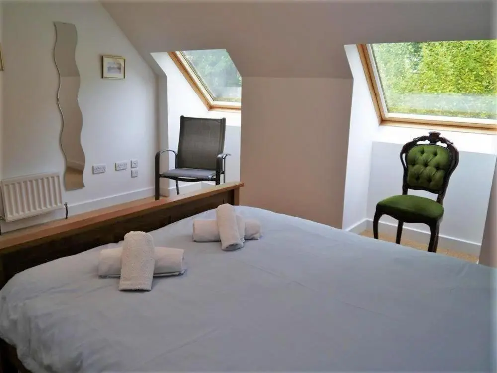 a bedroom with a large bed and two chairs at Osprey Cottage in Aviemore