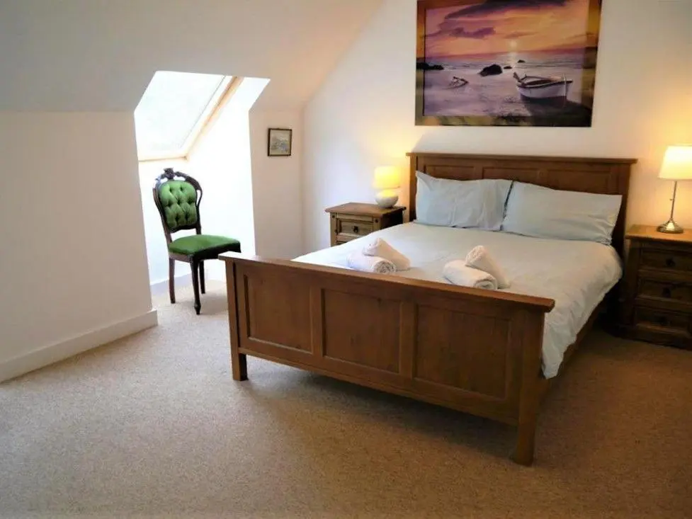 a bedroom with a large bed and a chair at Osprey Cottage in Aviemore