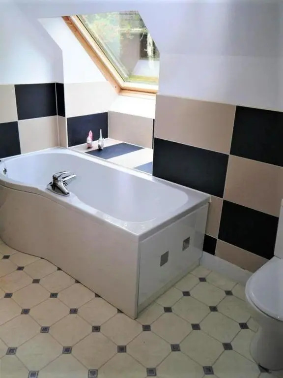 a bath tub in a bathroom with a window at Osprey Cottage in Aviemore