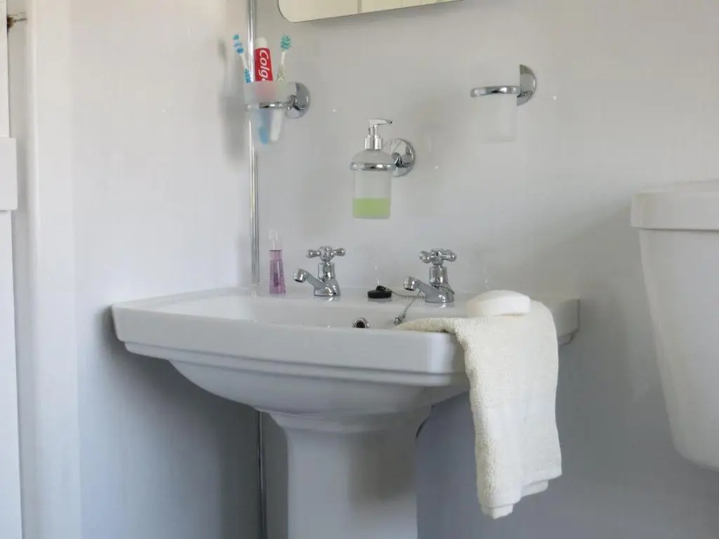 a white bathroom with a sink and a toilet at Sycamore Cottage in Boat of Garten