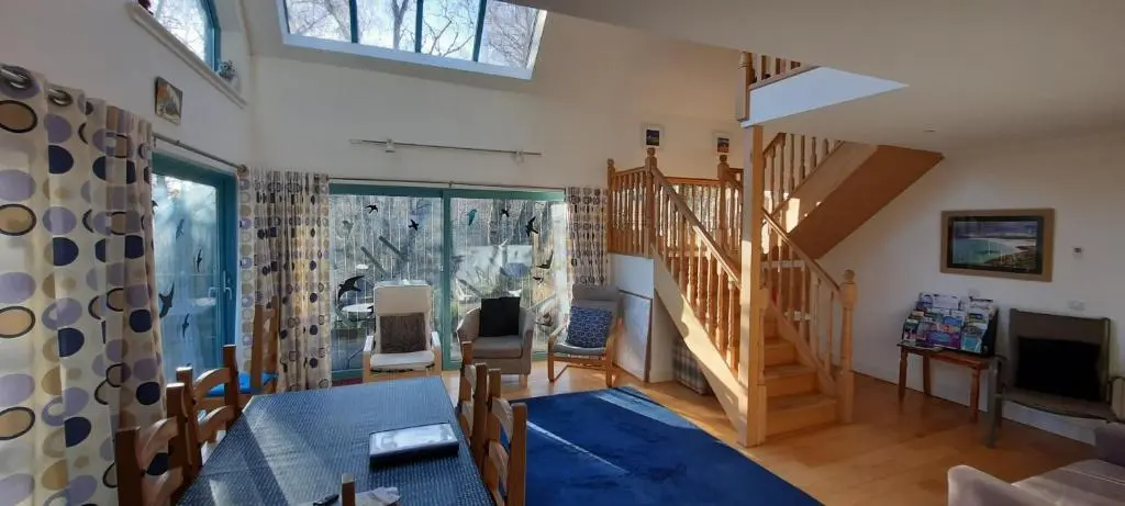 a living room with a staircase and a television at Ptarmigan Cottage in Aviemore