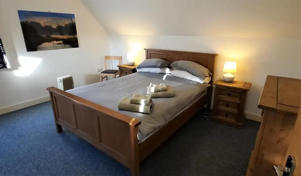 a bedroom with a large bed with two towels on it at Ptarmigan Cottage in Aviemore