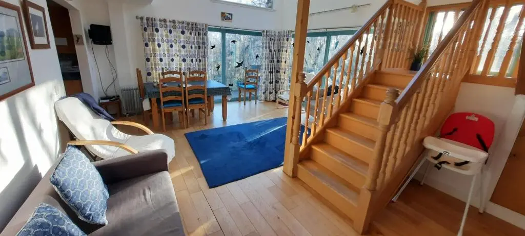 a living room with stairs and a dining room at Ptarmigan Cottage in Aviemore