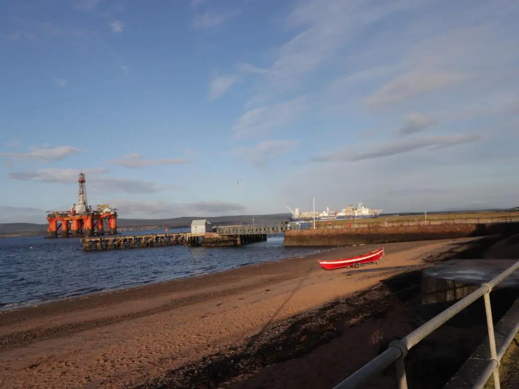 a red boat sitting on a beach next to the water at Flat 4, The Byre in Cromarty