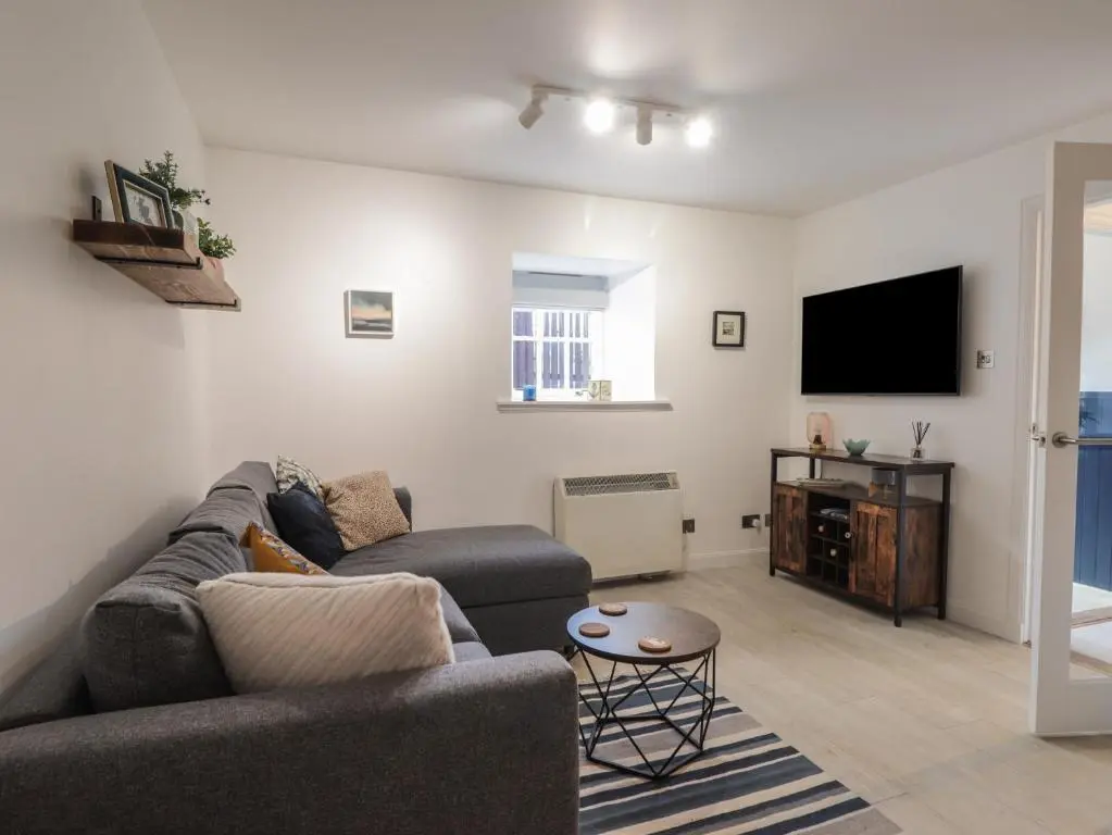 a living room with a couch and a flat screen tv at Flat 4, The Byre in Cromarty