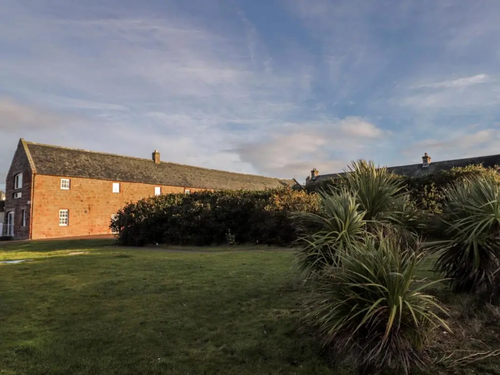 a large brick building with a grass yard at Flat 4, The Byre in Cromarty