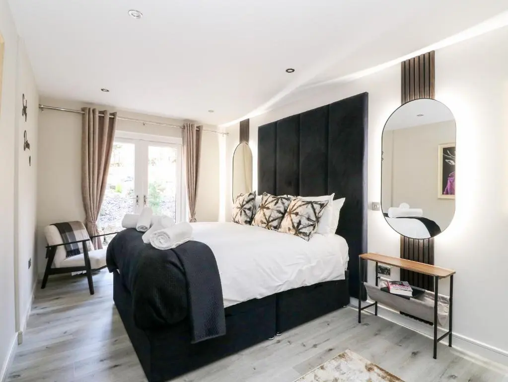 a bedroom with a large bed with a black headboard at Heilan Roo in Pitlochry