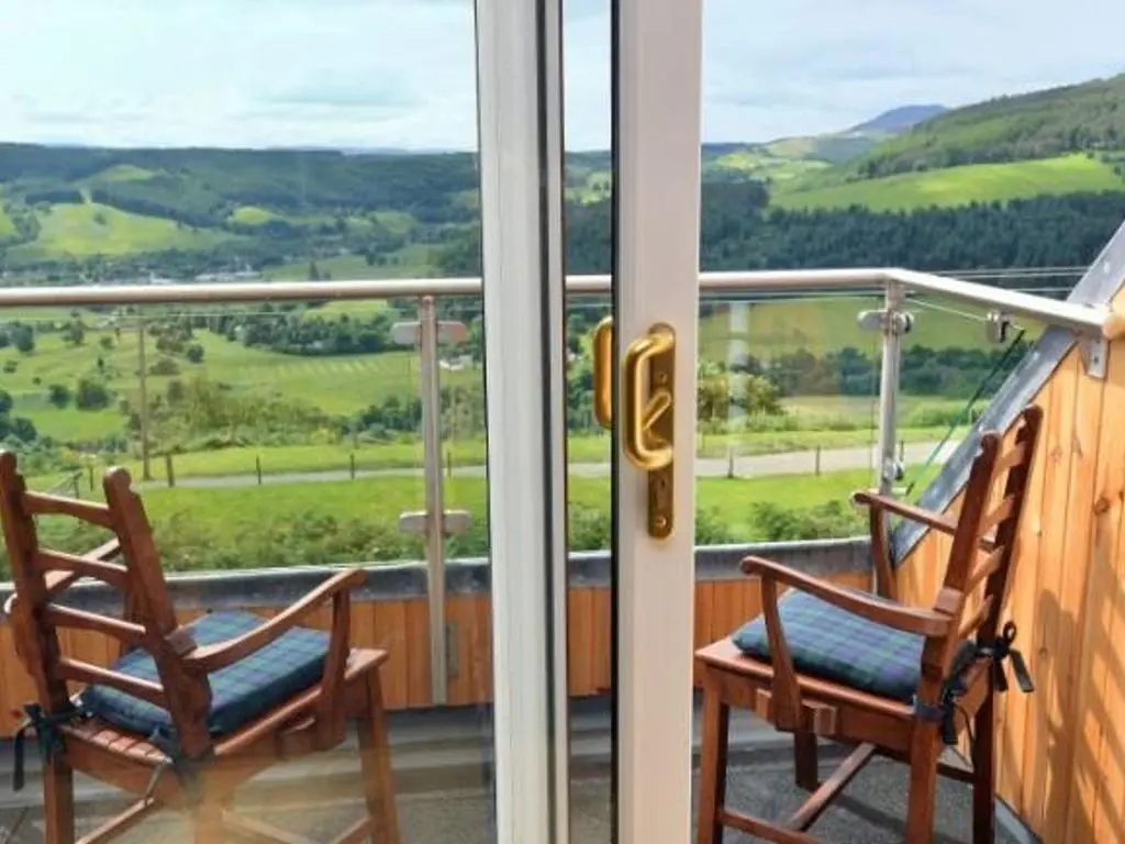 two chairs sitting on a balcony with a view at Glen View Lodge in Inverness