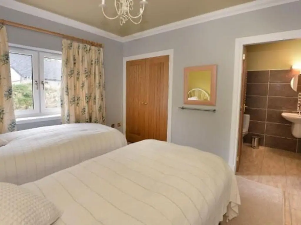 a bedroom with two white beds and a window at Glen View Lodge in Inverness