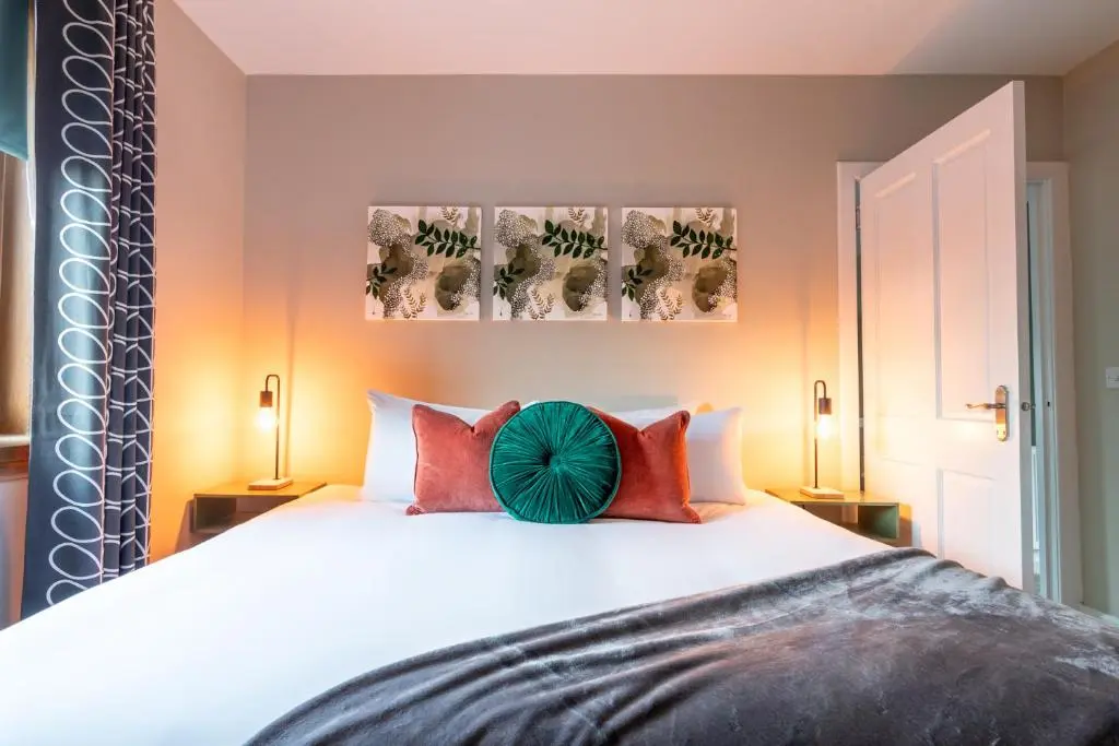 a bedroom with a large white bed with red pillows at Ness at the Park in Inverness