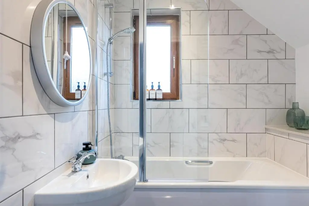 a bathroom with a sink and a tub and a mirror at Ness at the Park in Inverness