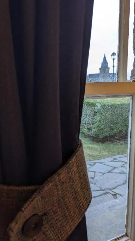 a curtain in front of a window with a view at Historic character cottage in central Dornoch in Dornoch