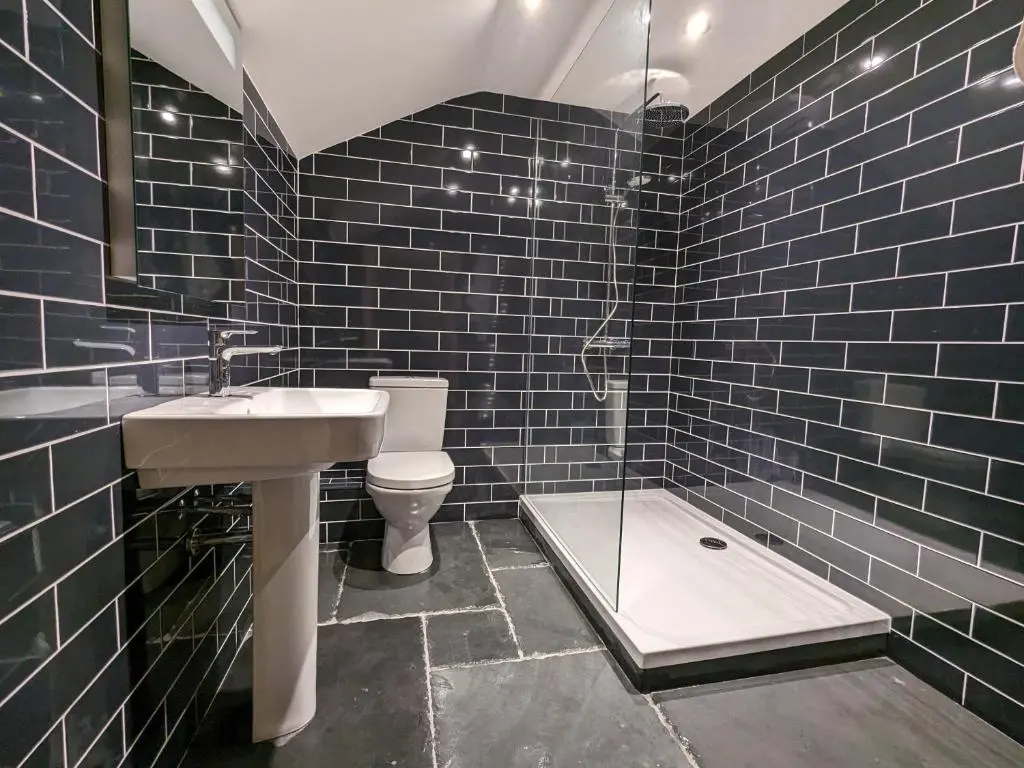 a bathroom with a sink and a toilet and blue tiles at Historic character cottage in central Dornoch in Dornoch