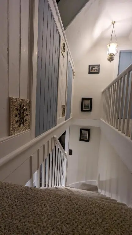 a hallway with a stairway with a white stair case at Historic character cottage in central Dornoch in Dornoch