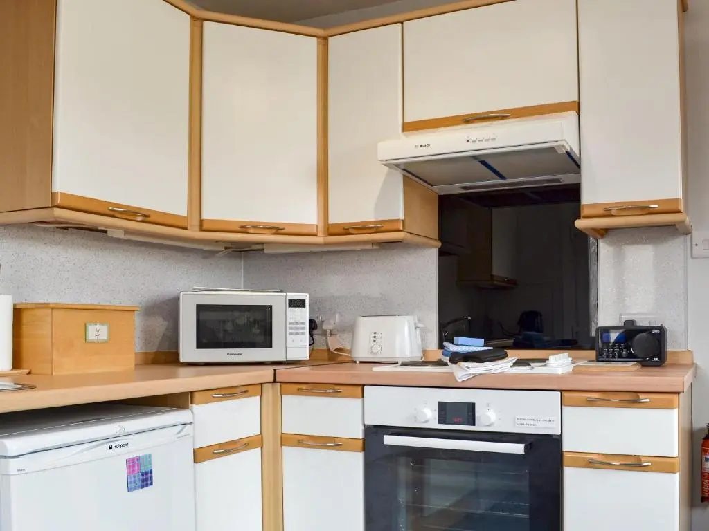 a kitchen with white appliances and wooden cabinets at Cedar Cottage - Uk32633 in Grantown on Spey
