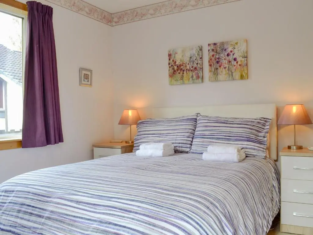 a bedroom with a bed with two night stands and two lamps at Cedar Cottage - Uk32633 in Grantown on Spey