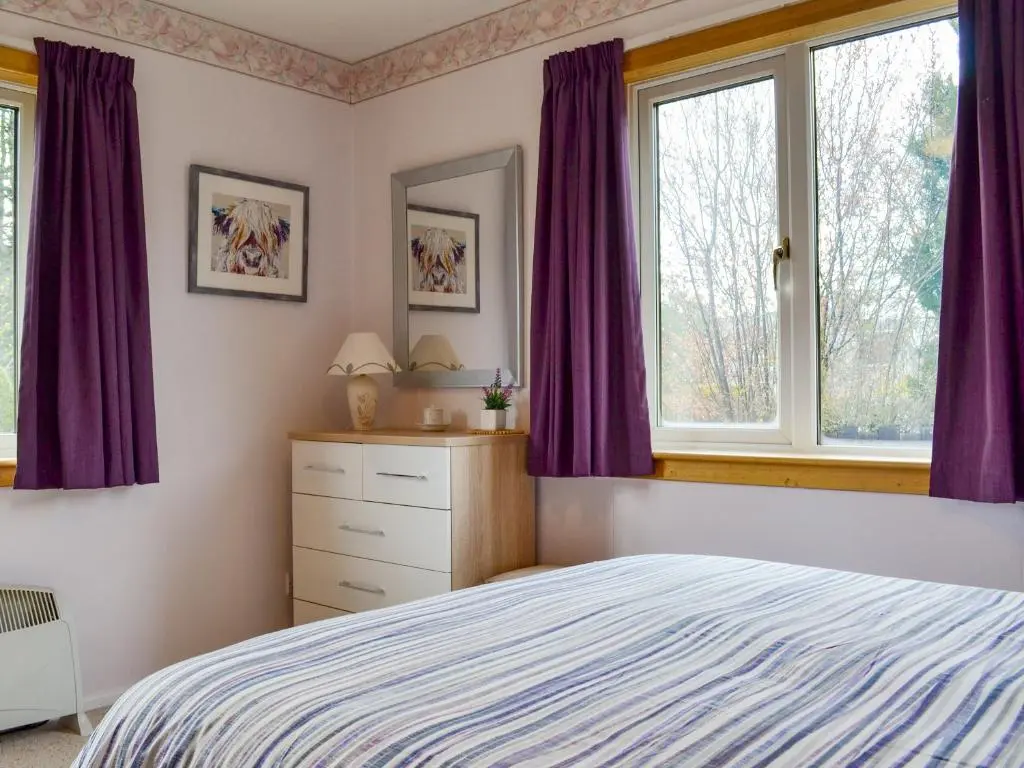 a bedroom with purple curtains and a bed at Cedar Cottage - Uk32633 in Grantown on Spey