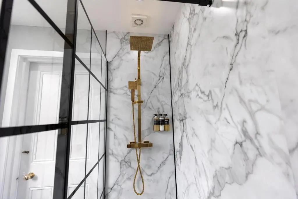 a bathroom with white marble walls and a shower at The Crossing in Kingussie