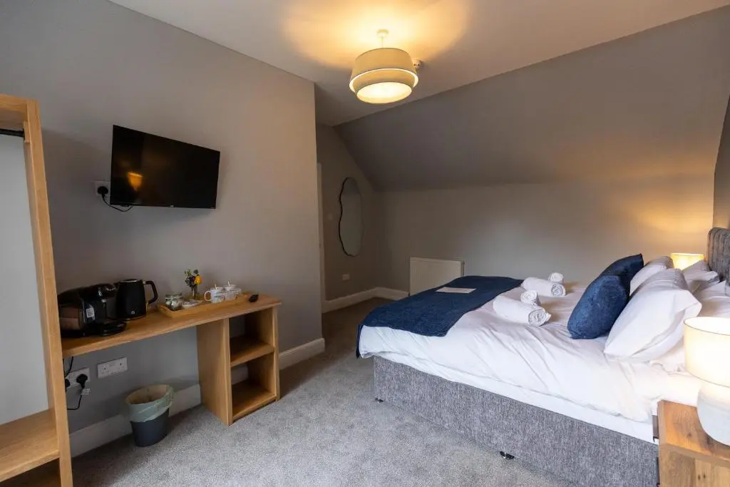 a bedroom with a bed and a desk and a television at The Crossing in Kingussie