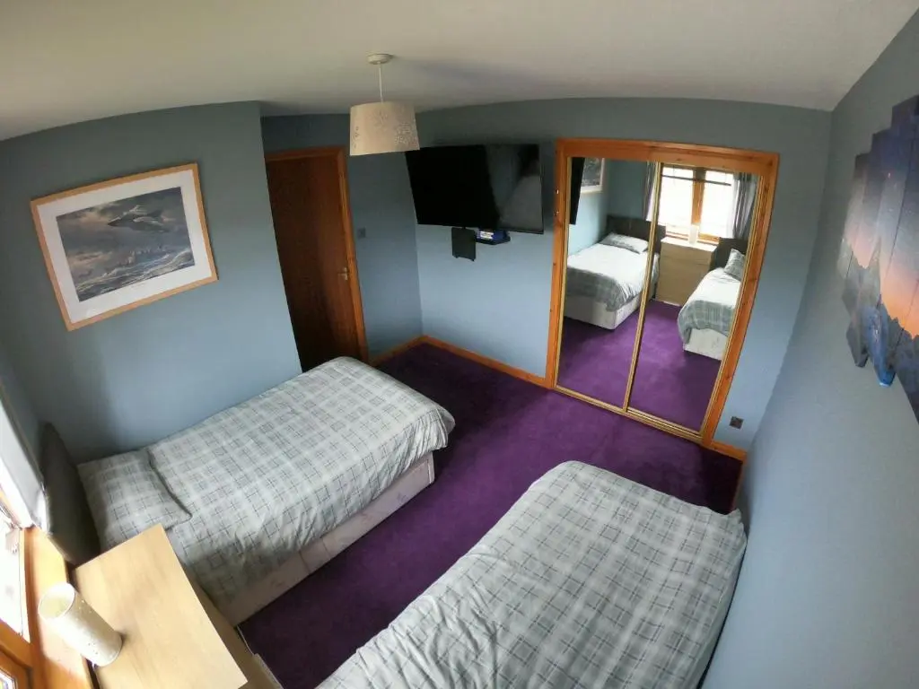 a small room with two beds and a mirror at Mountain View No12 in Aviemore