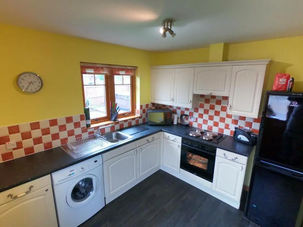 a kitchen with white cabinets and a black counter top at Mountain View No12 in Aviemore