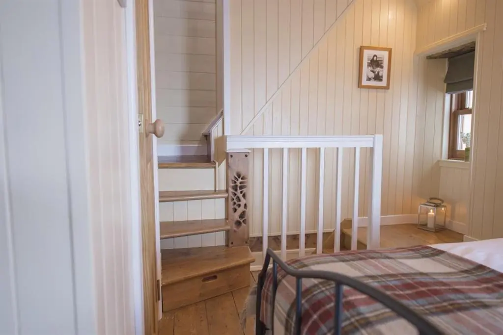 a bedroom with a staircase and a bed in a room at The Wee House in Pennan