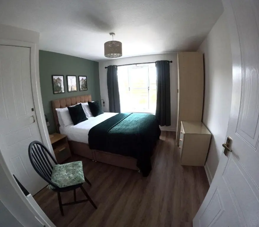 a bedroom with a bed and a window and a chair at Orange Squirrel Lodge in Aviemore