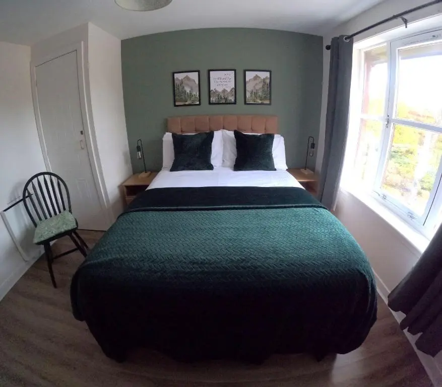 a bedroom with a large bed and two windows at Orange Squirrel Lodge in Aviemore