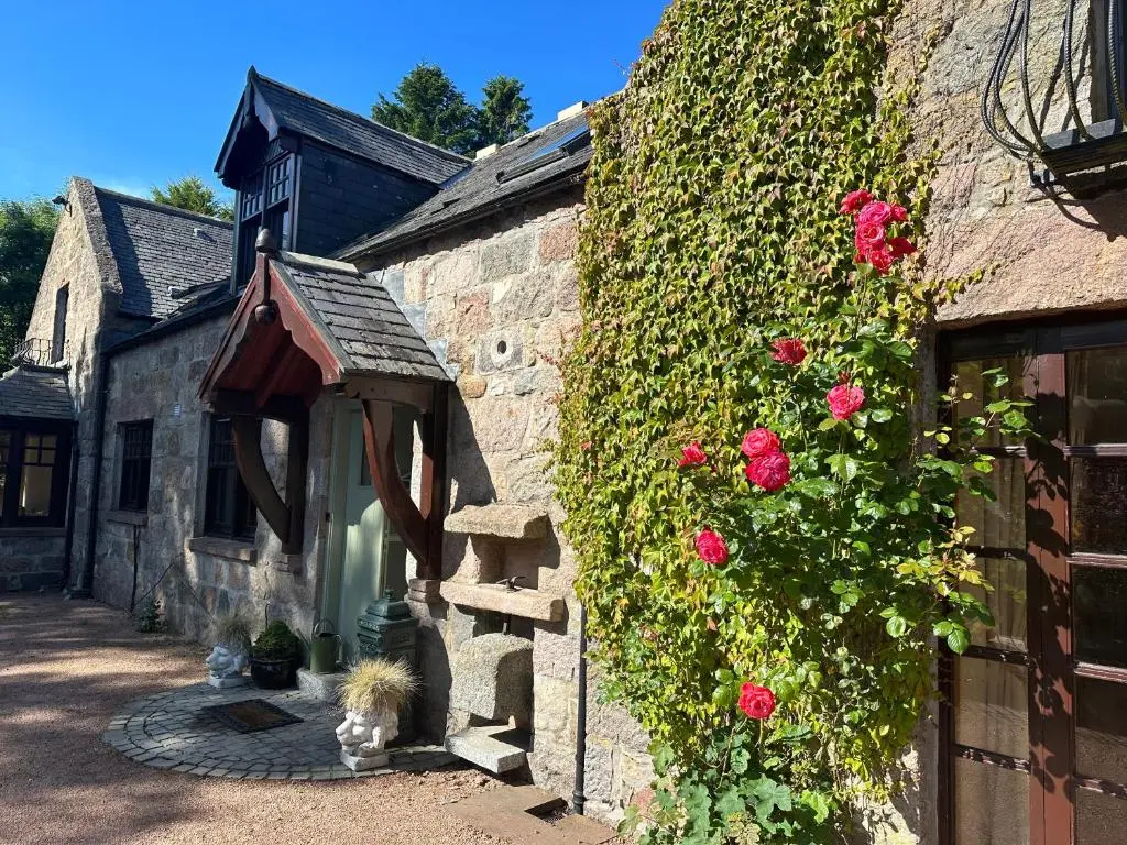 a dog sitting in the doorway of a building with roses at Awakening Alchemy Retreat Centre in Inverurie