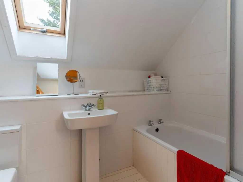 a white bathroom with a sink and a bath tub at Holiday Home Muir Edge by Interhome in Nethy Bridge