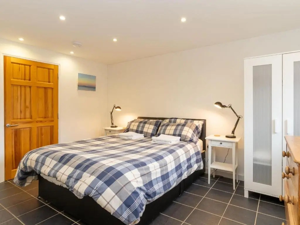a bedroom with a bed and two lamps on two tables at Holiday Home Muir Edge by Interhome in Nethy Bridge