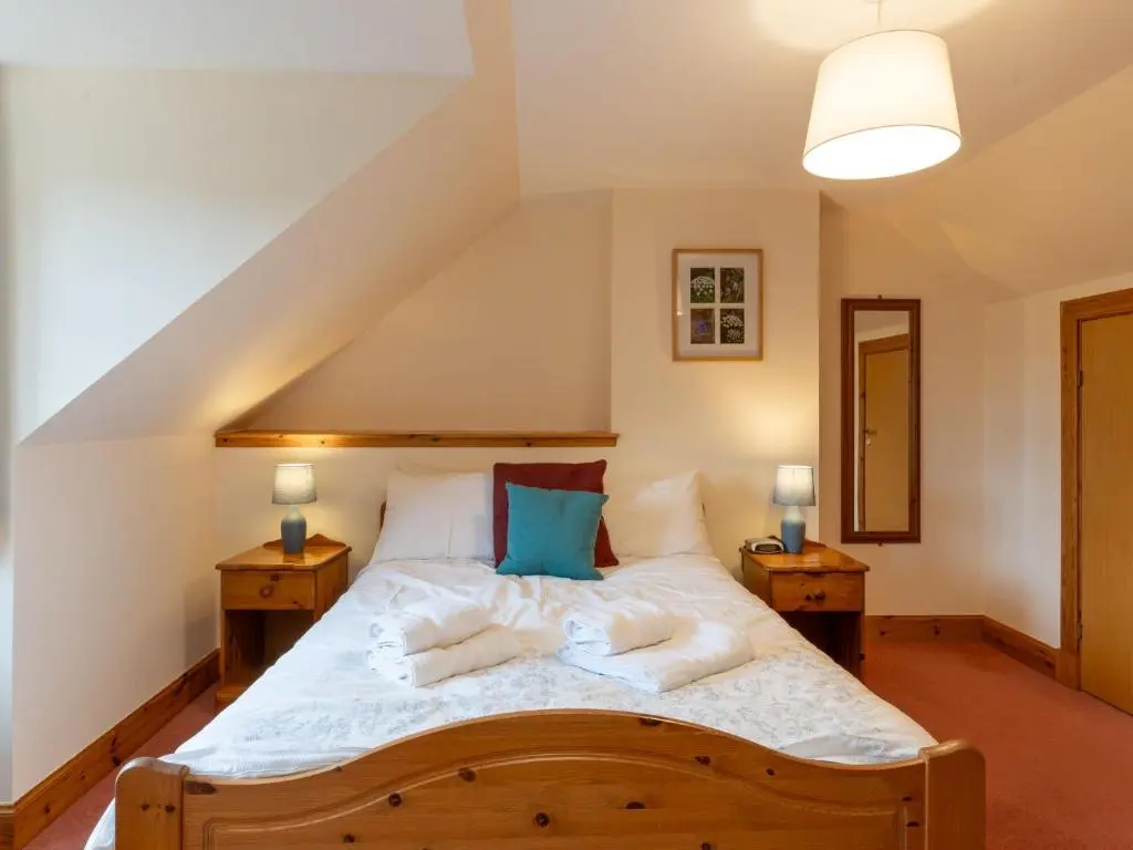 a bedroom with a large bed with two night stands at Villa Osprey House by Interhome in Nethy Bridge