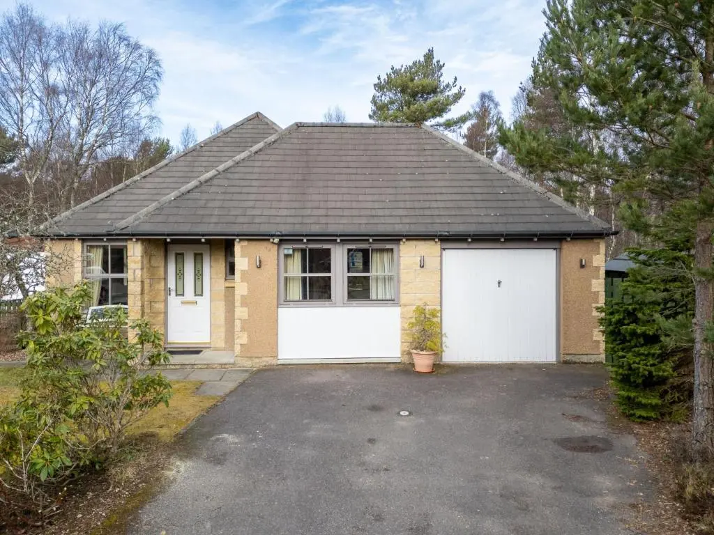 a brick house with two white garage doors at Holiday Home Falcon Lodge by Interhome in Aviemore